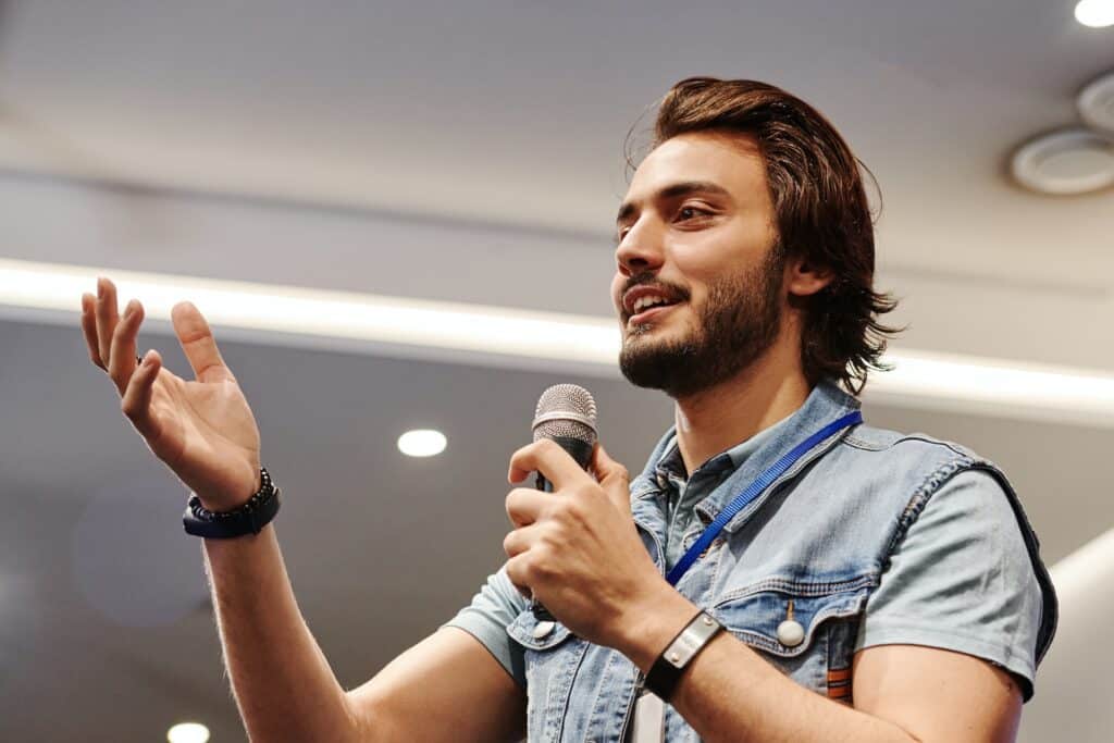 man-in-denim-polo-shirt-speaking-into-microphone