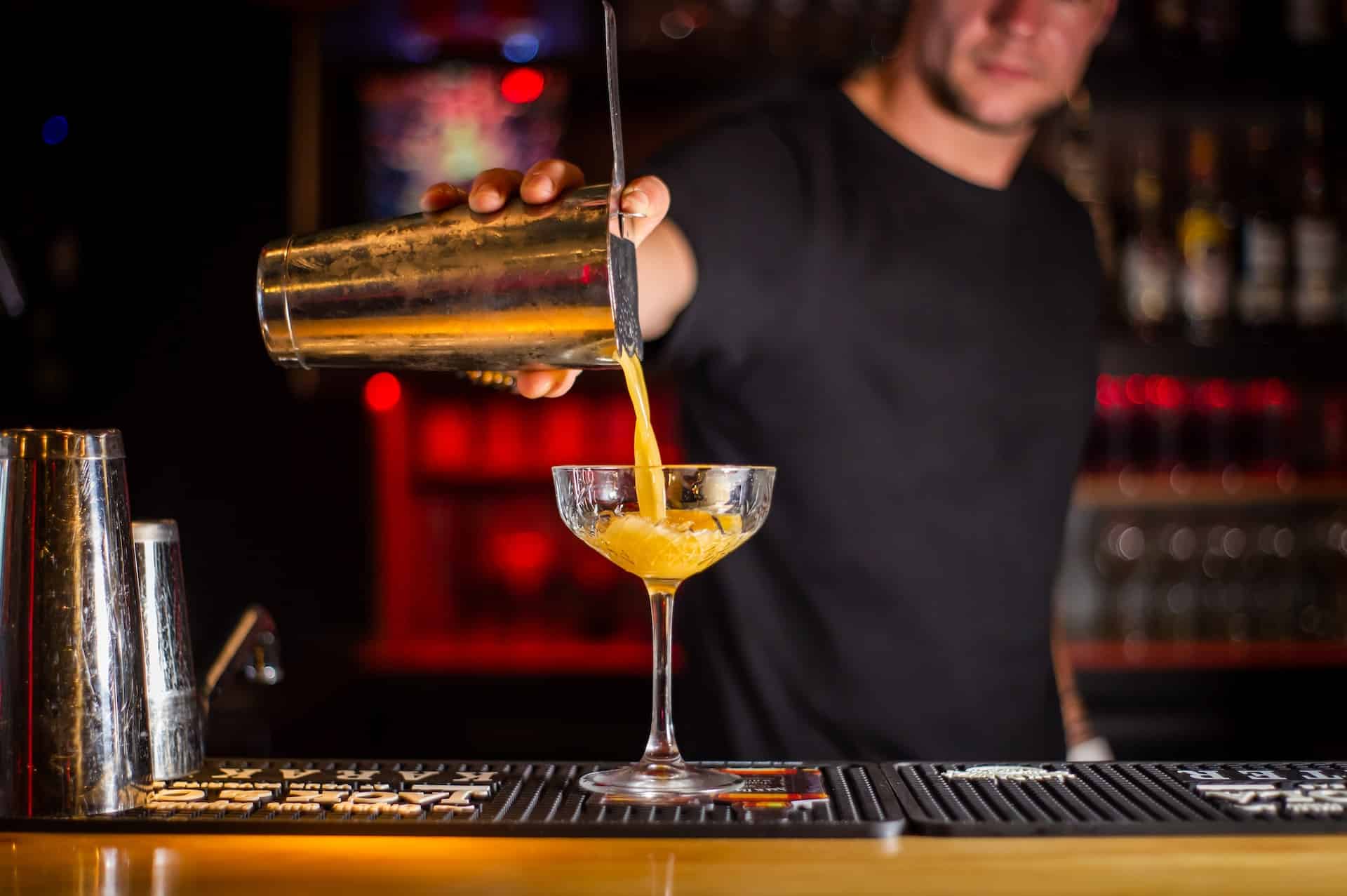 bartender pouring orange cocktail drink
