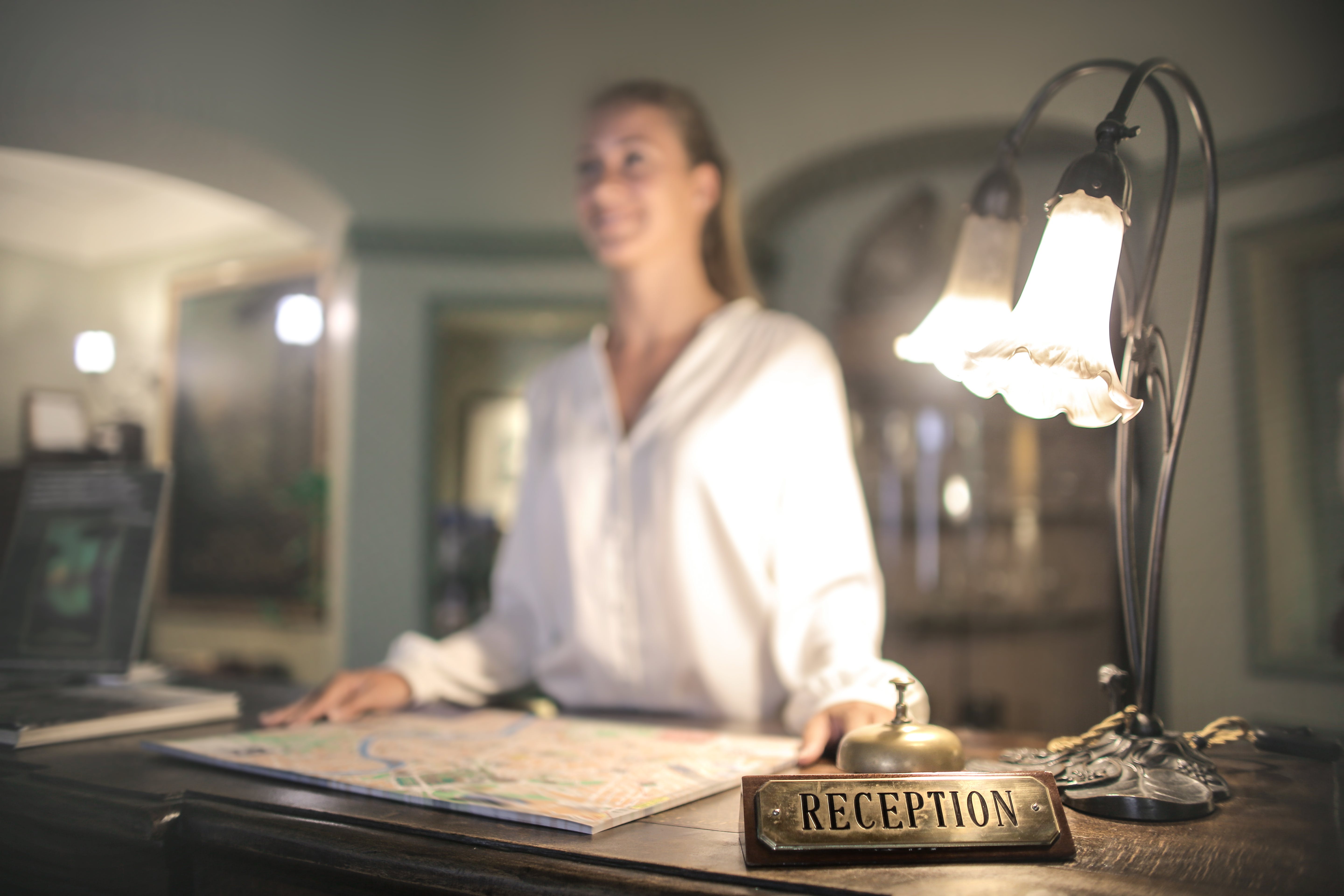 photo-of-a-reception-sign-and-a-female-receptionist-at-a-hotel