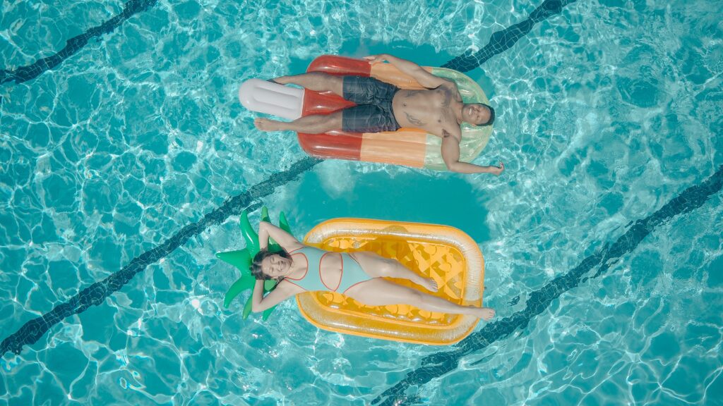 Two people floating on rafts in a swimming pool