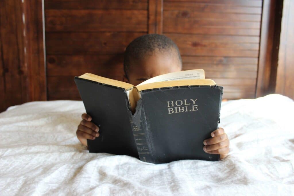A boy reading the Bible in bed