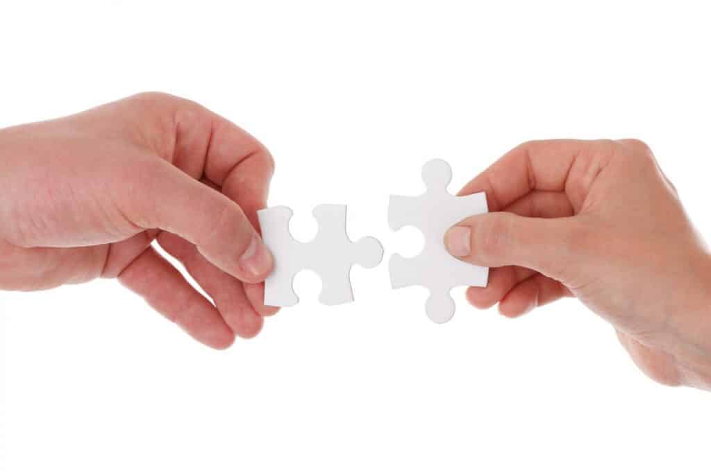 two-hands-linking-white-jigsaw-puzzles-together