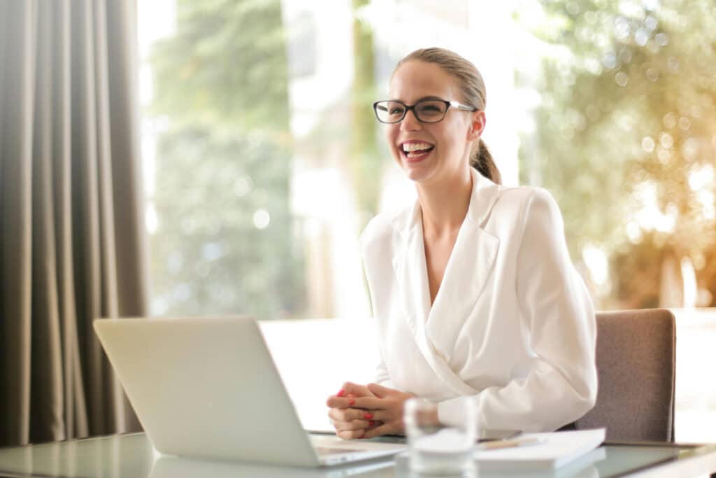 Woman smiling and sitting in front of laptop