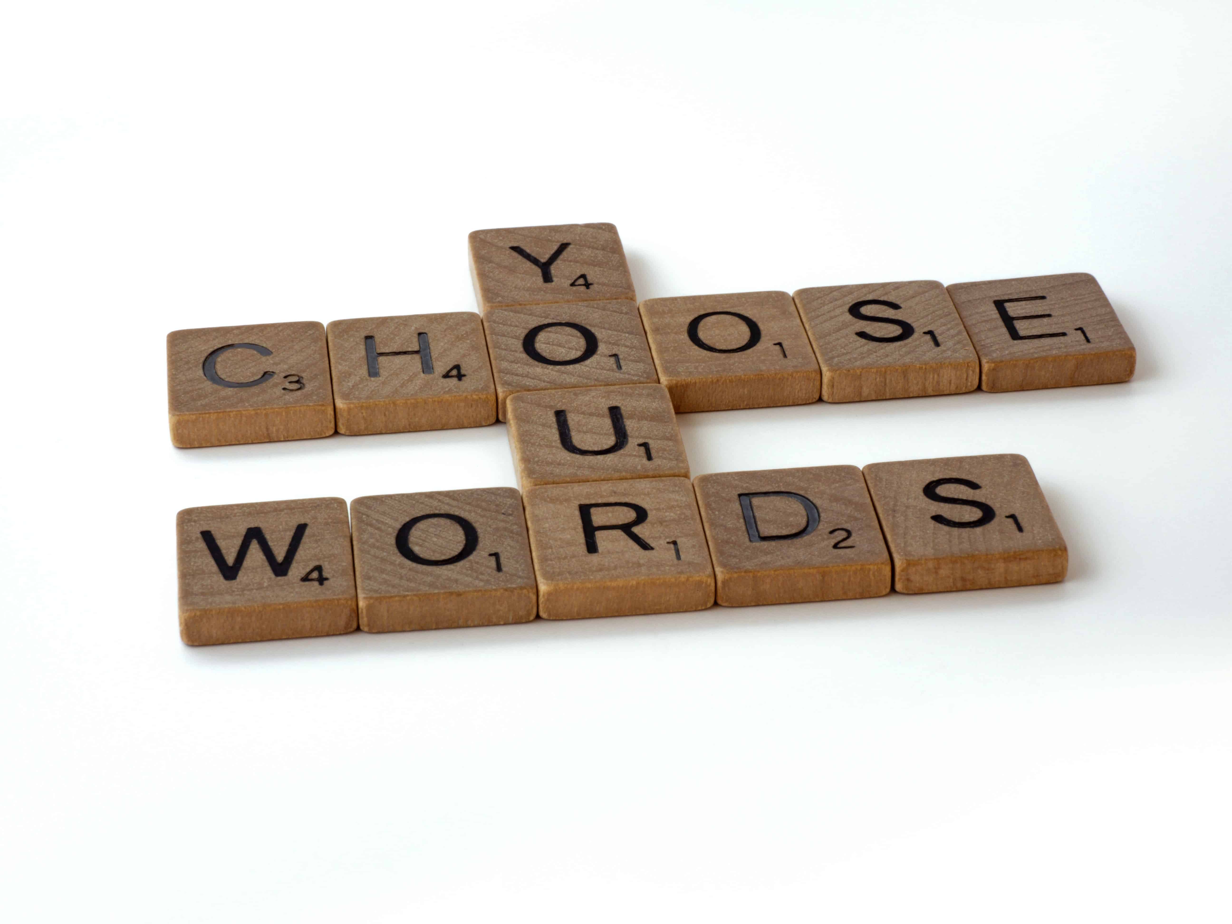 Scrabble tiles laid out reading "choose your words"