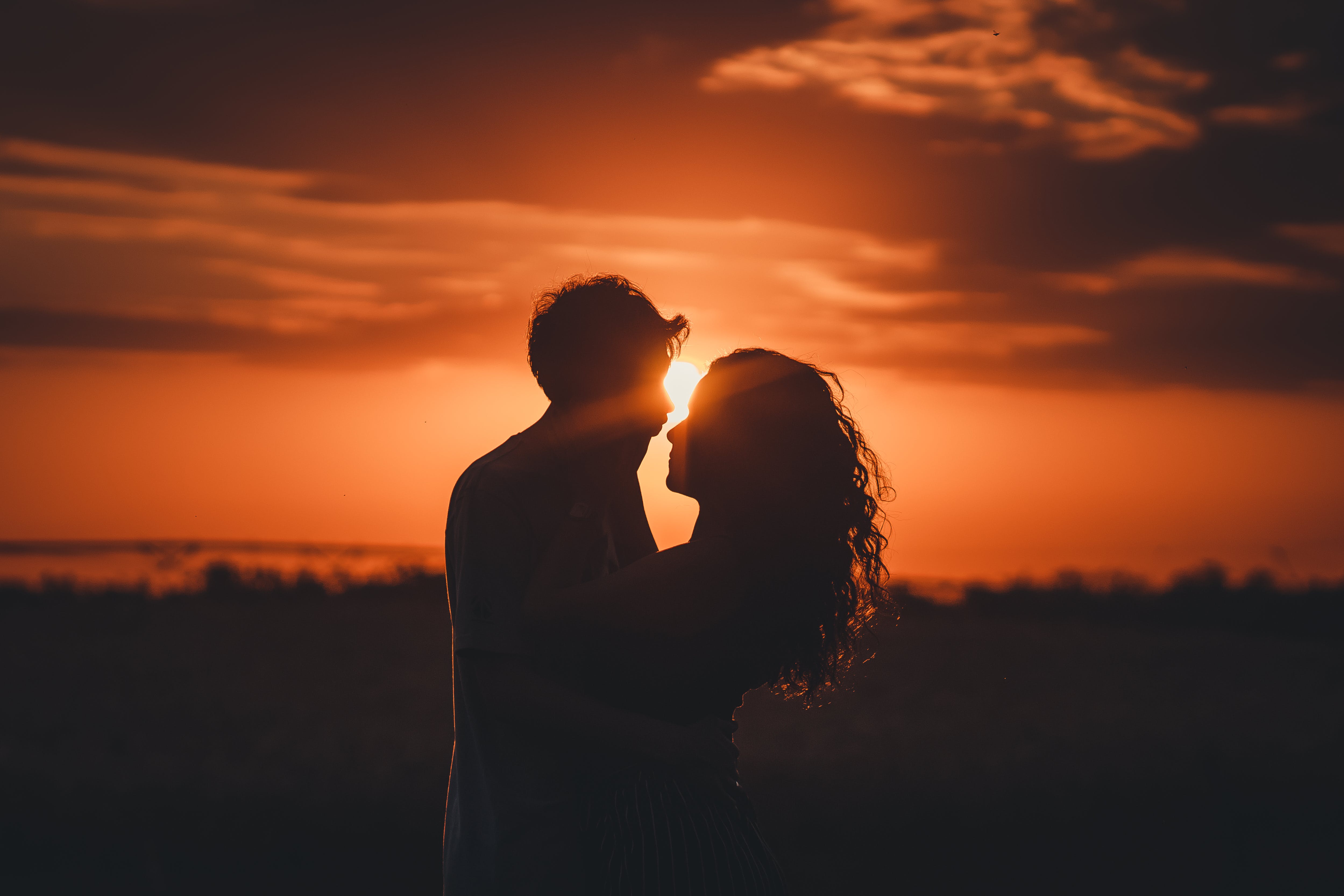 A couple embraces in front of the setting sun