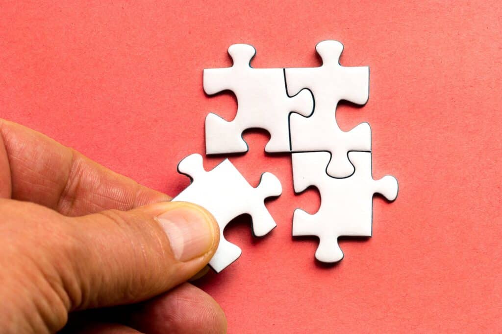 hand-putting-last-jigsaw-puzzle-piece-against-bright-red-background