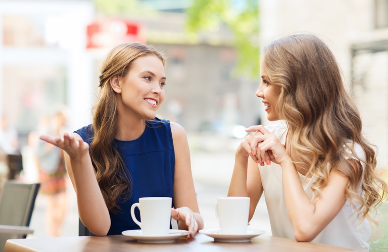Two woman chatting in a cafe with coffee cups on the table