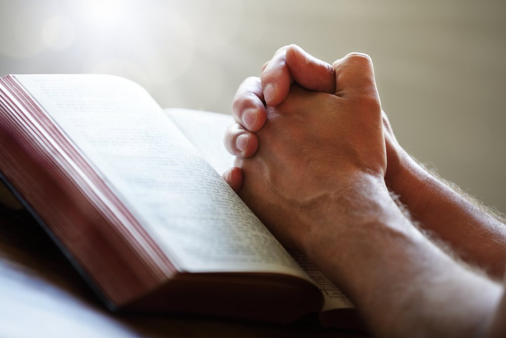 Hands folded on an open Bible