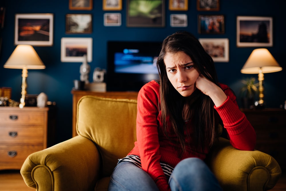 Woman sitting on her couch in a bad mood