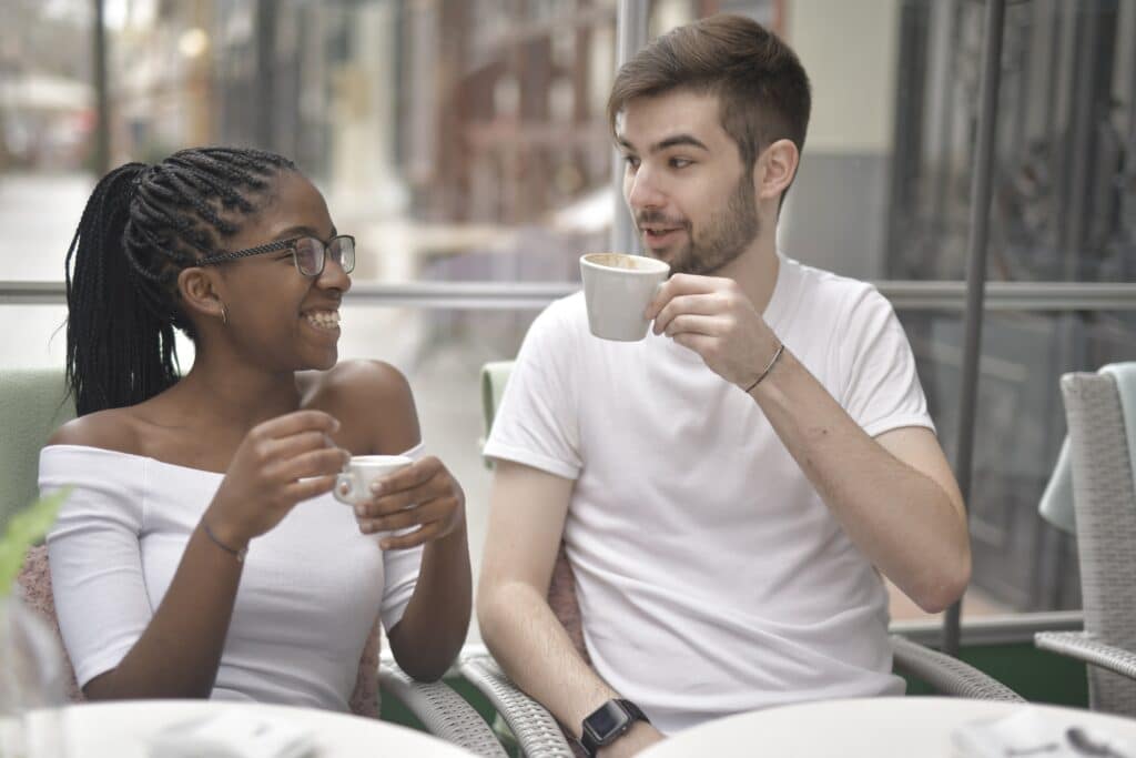 a guy and a girl drinking coffee in cafeteria in daylight