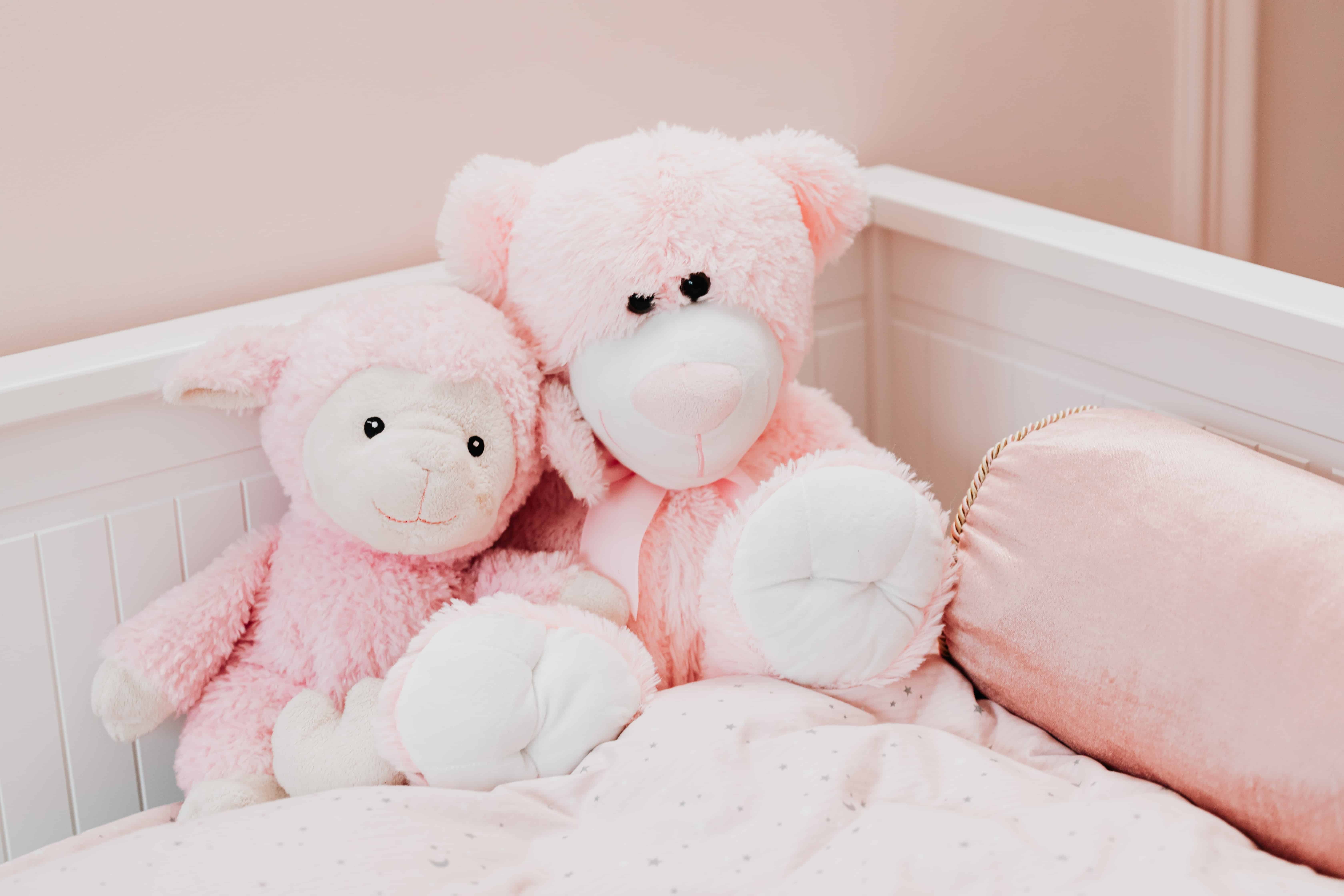 pink-lamb-and-teddy-stuffed-animal-toys-on-a-bed