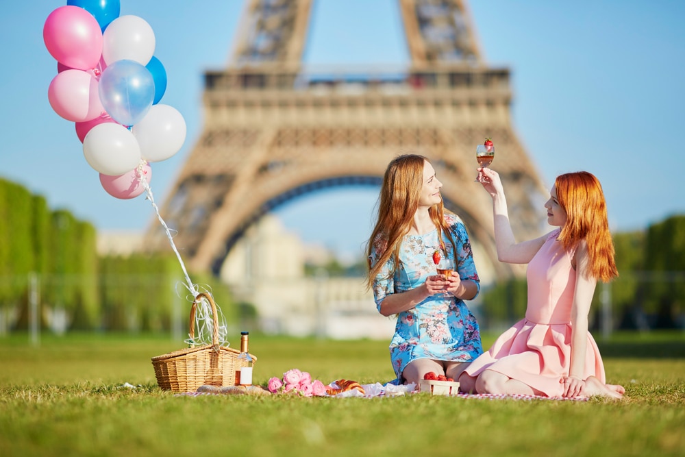 Two women having a picnic near the Eiffel tower.