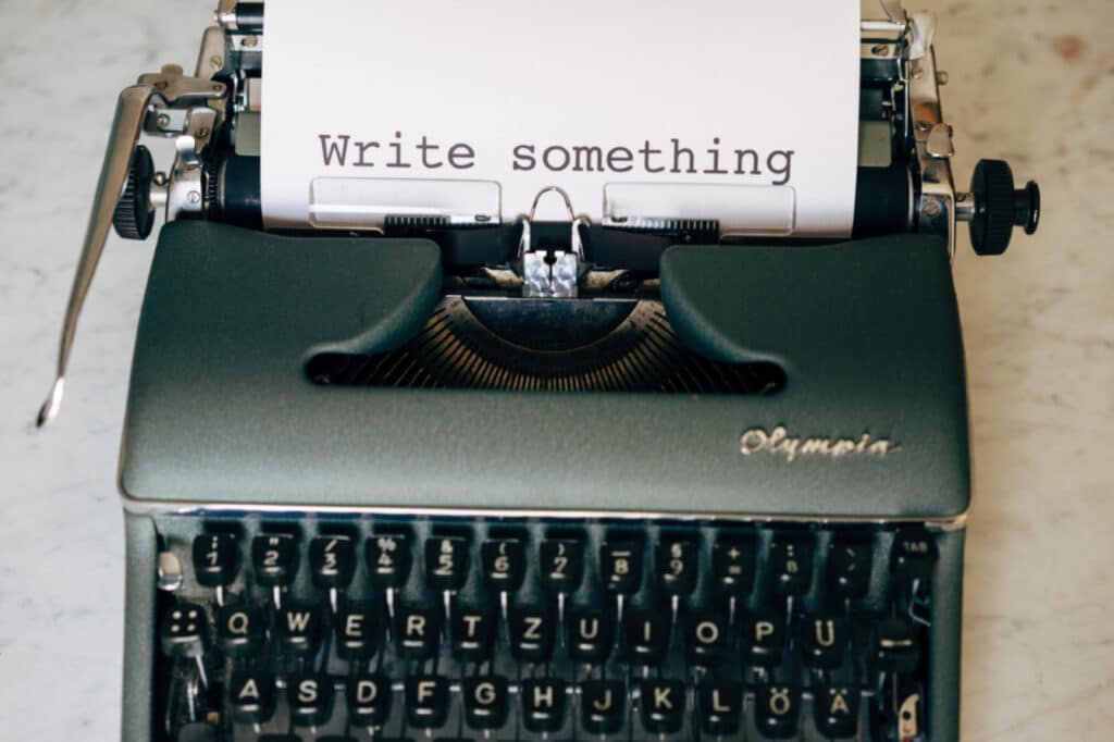 Green typewriter with paper saying "write something"