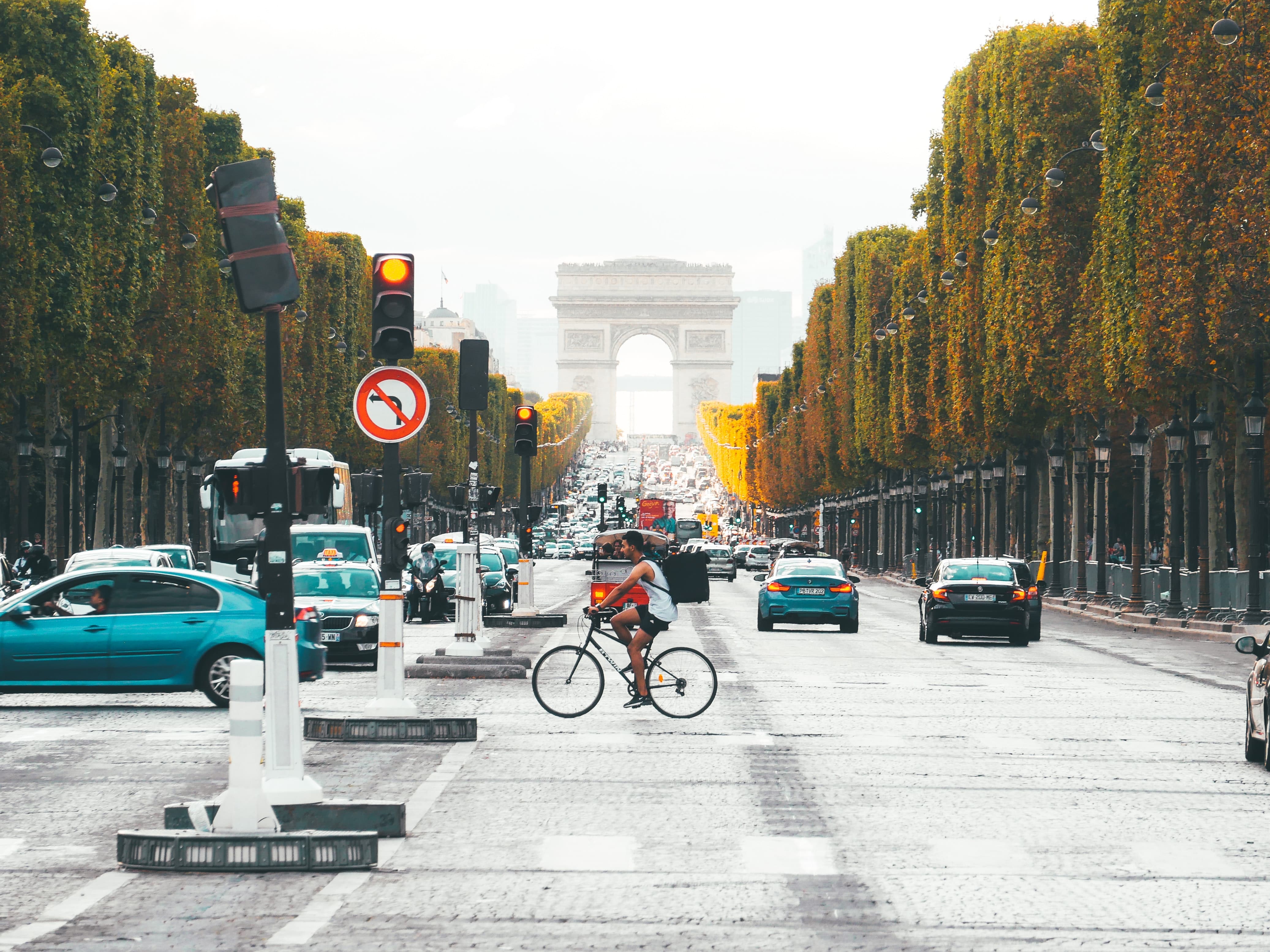 man-on-a-bicycle-crossing-the-road-leading-to-the-Arc-de-Triomphe-de-l'Étoile-in-Paris-busy-traffic