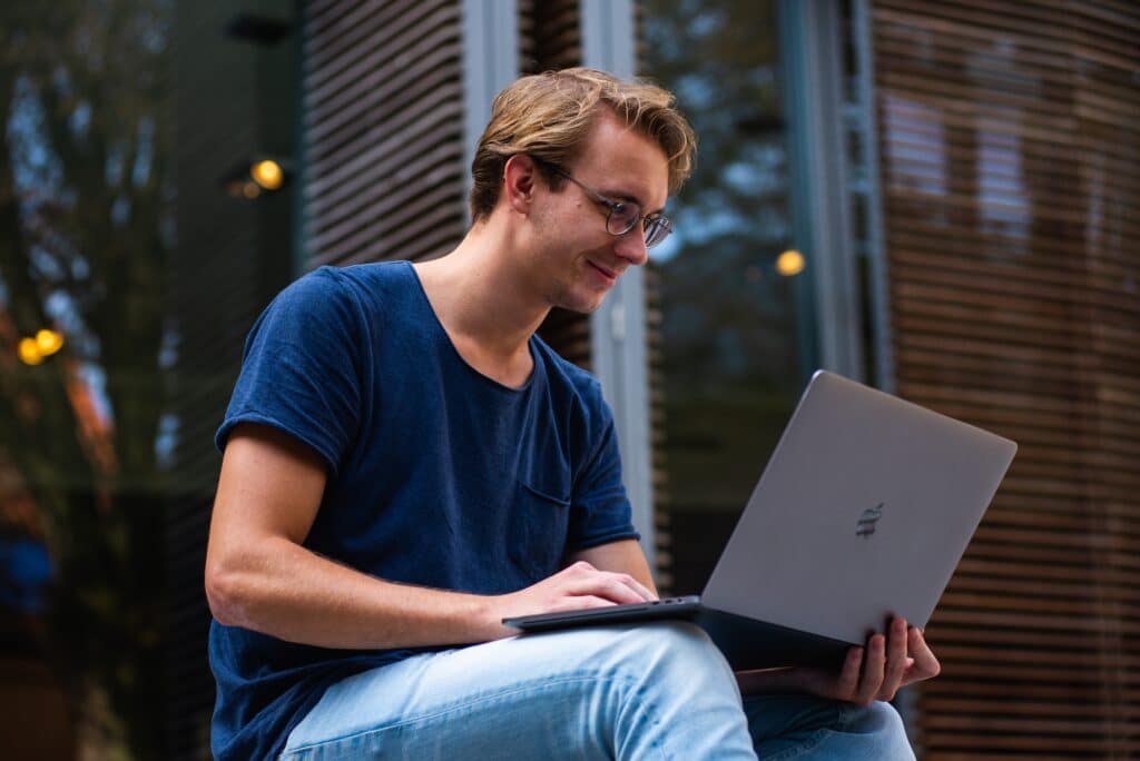 selective-focus-photo-of-a-man-sitting-outside-using-a-laptop