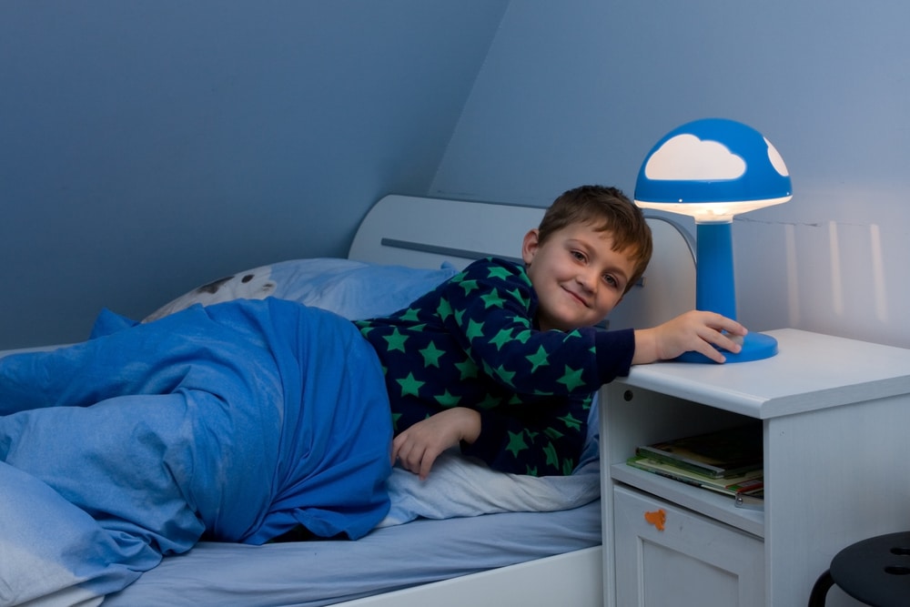 boy in bed about to turn off his lamp