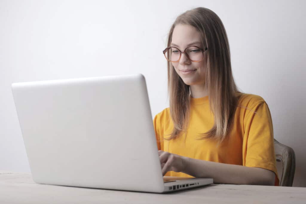 Woman in orange shirt using laptop
