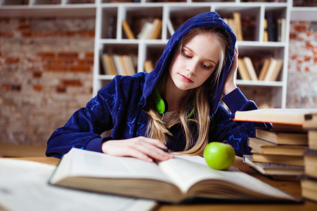 woman-wearing-blue-hoodie-and-green-headphones-studying-books