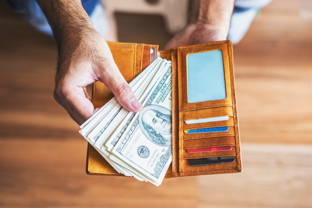 man-pulling-hundred-dollar-bills-out-of-wallet
