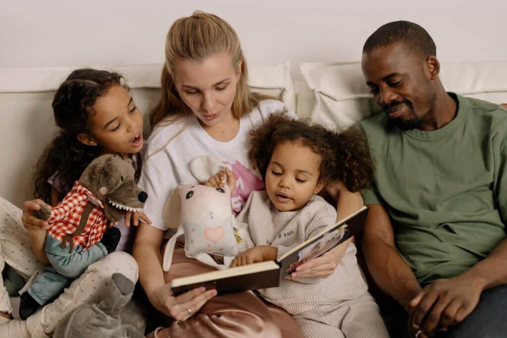 multiracial-family-reading-book-together-in-bed
