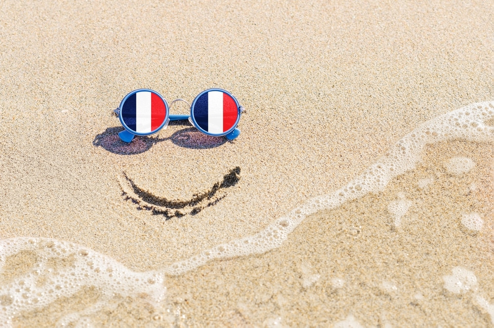 smiley-face-in-sand-with-french-flag-glasses
