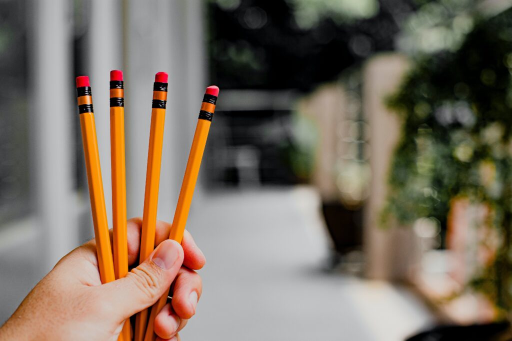 close-up-picture-of-a-hand-holding-four-pencils-with-a-blurry-background