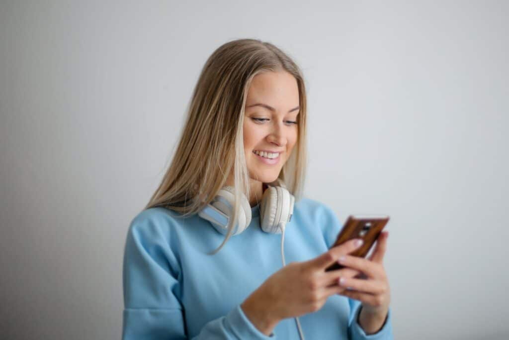 woman-in-a-blue-sweater-smiling-looking-down-at-her-phone