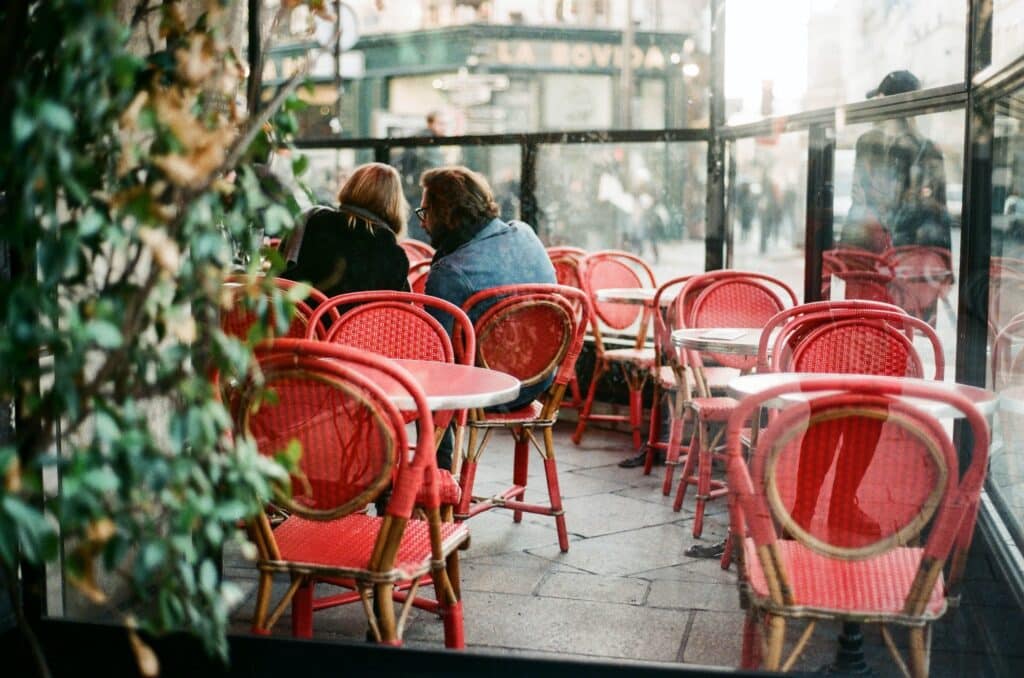 two-people-in-cafe-talking-with-chairs-and-plants-in-the-foreground