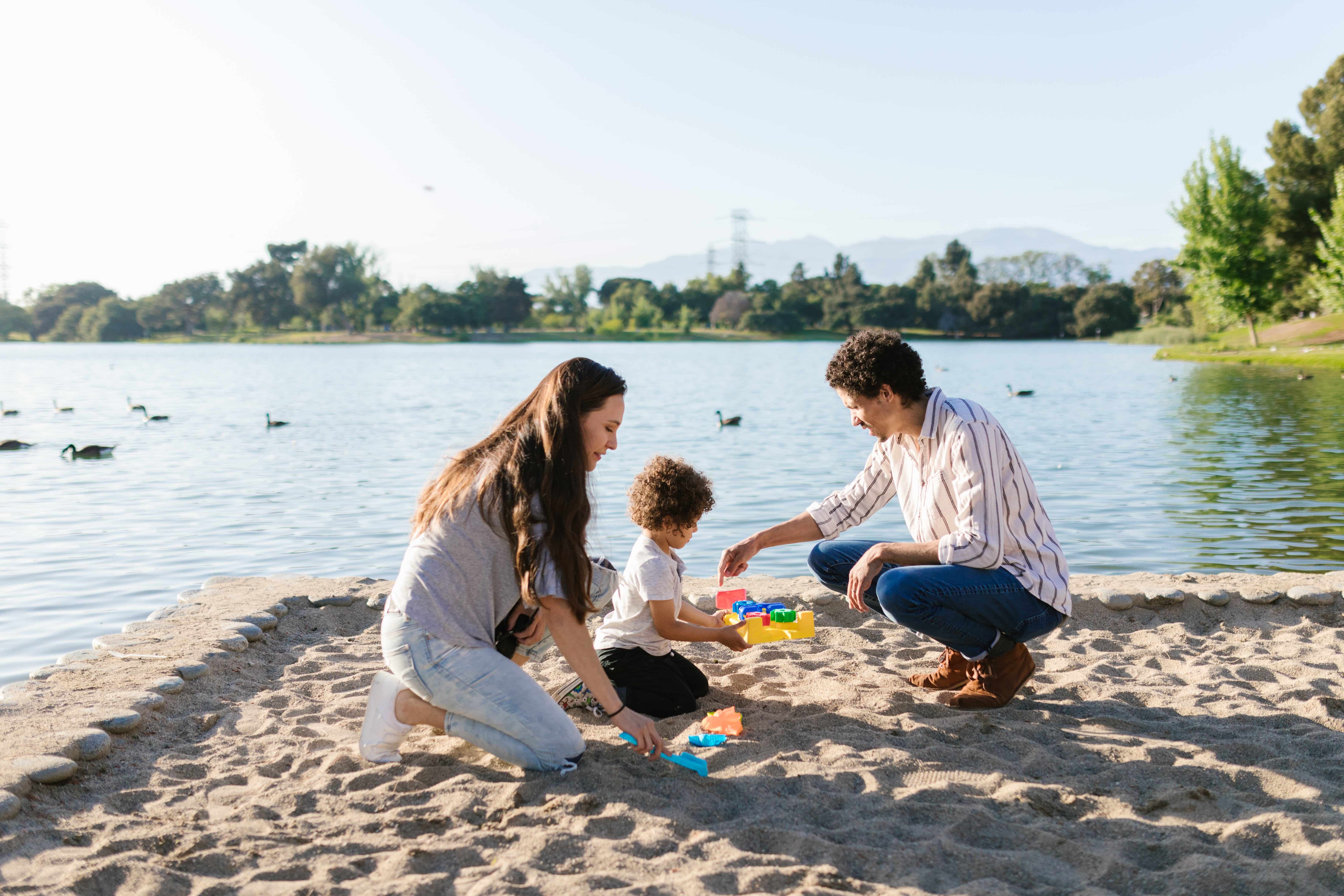 picture-of-a-man-and-woman-playing-with-their-young-son-in-the-sand-next-to-the-water