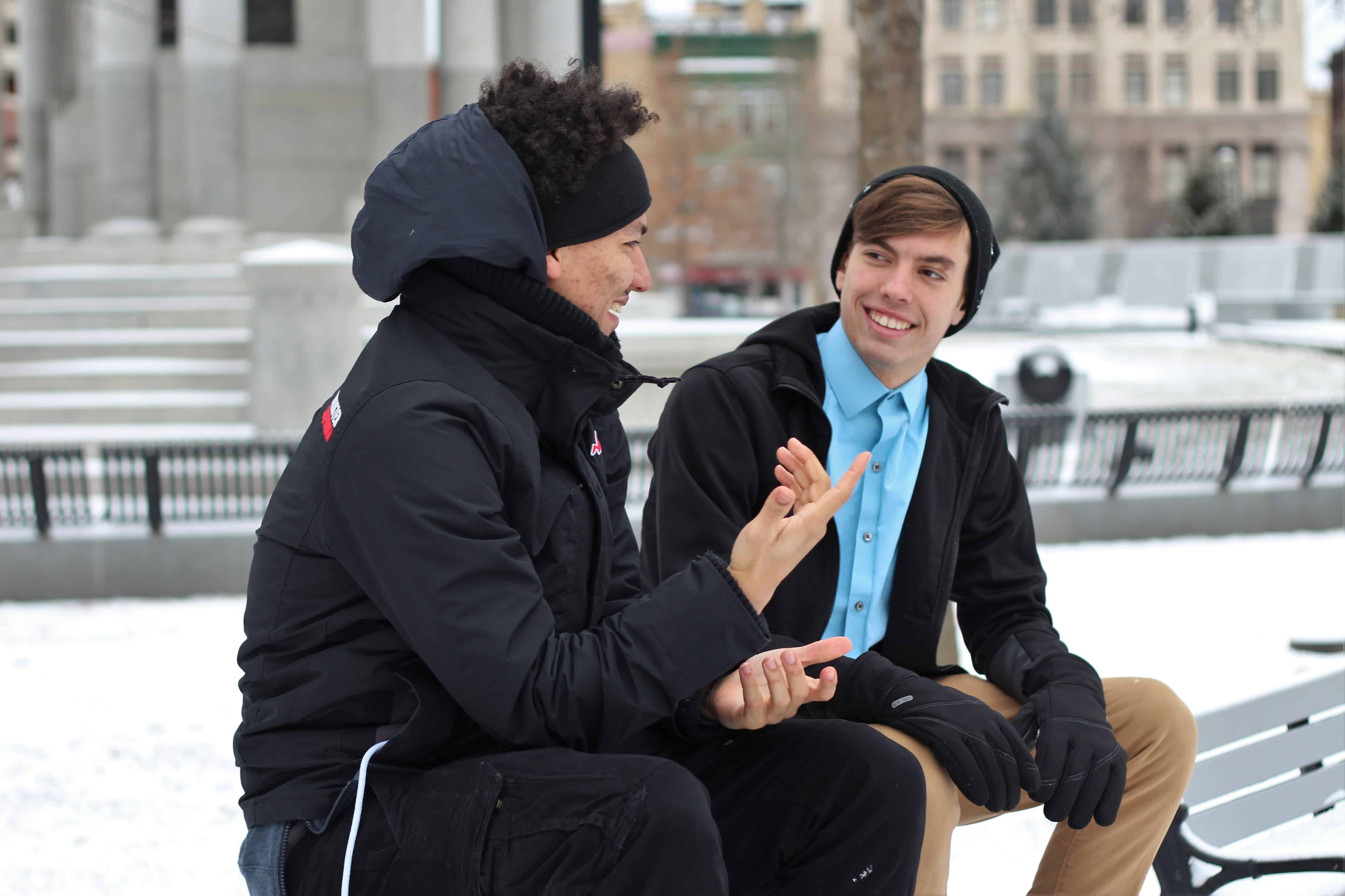 Two young men sitting outside and talking
