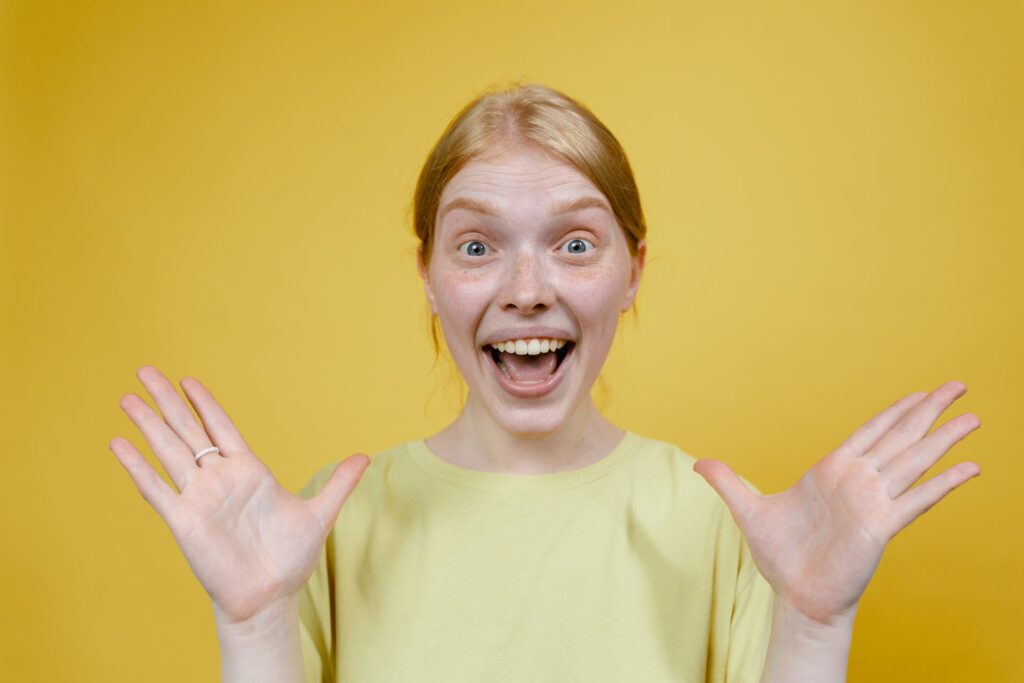 woman-with-open-mouth-holding-hands-apart-against-yellow-background