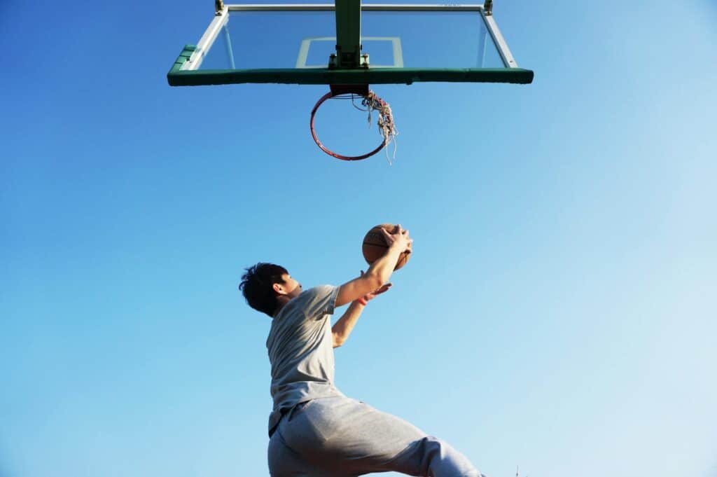 low-angle-shot-of-young-man-about-to-dunk-basketball-into-basket