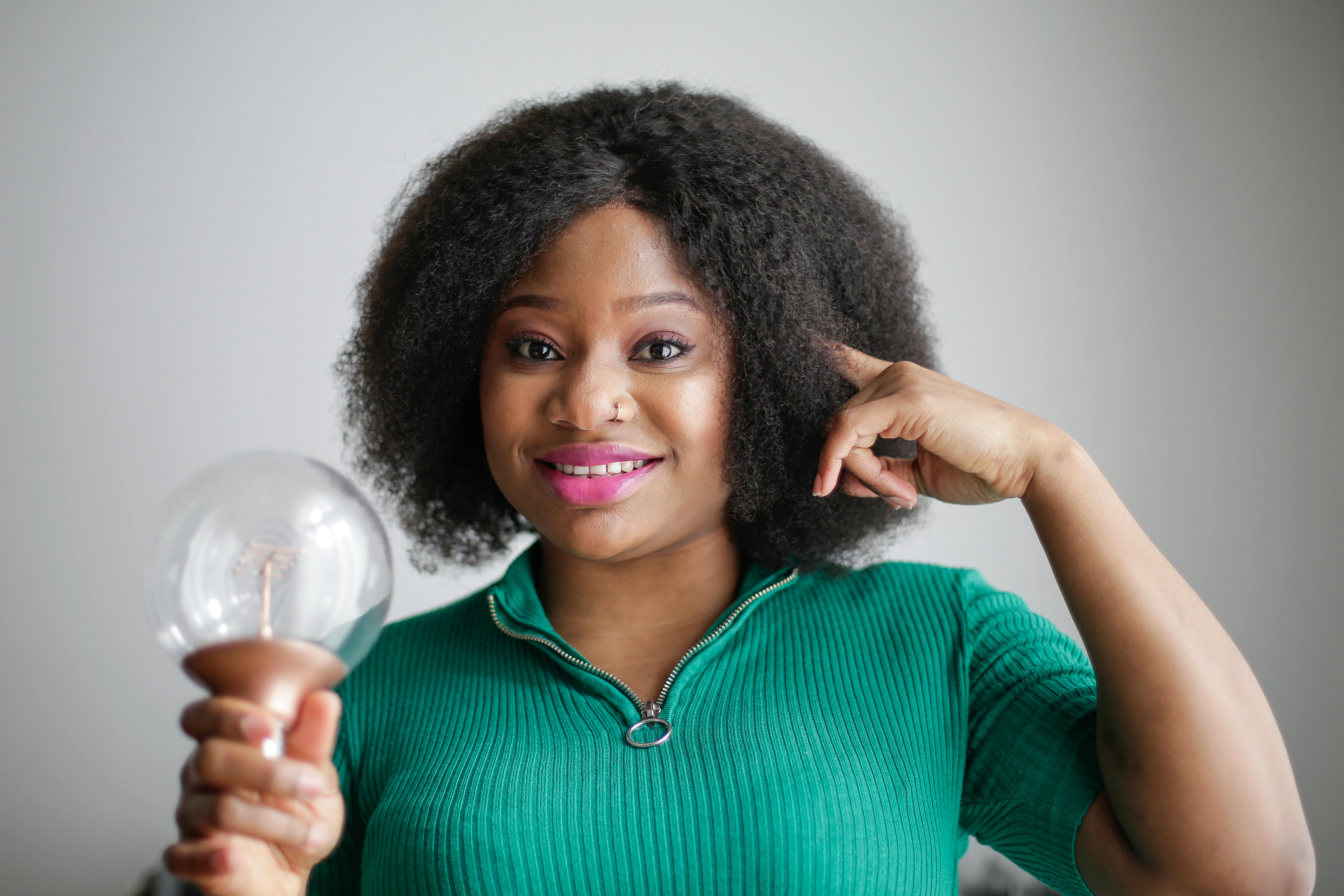 A woman holds a light bulb and points to her brain