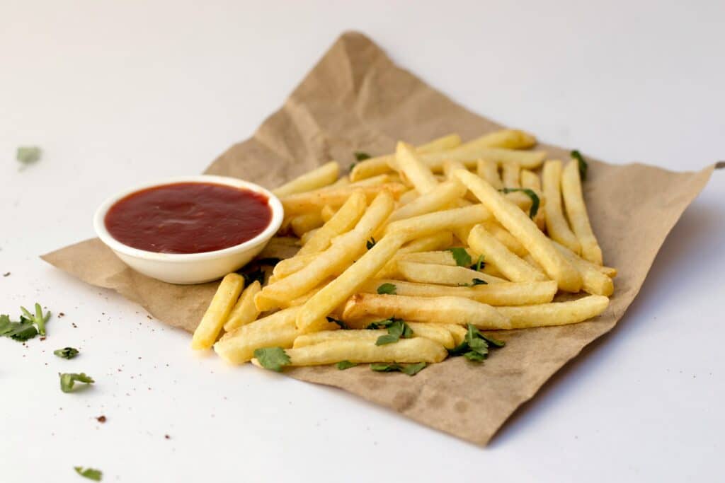 photo-of-french-fries-on-brown-paper-with-ketchup-dip