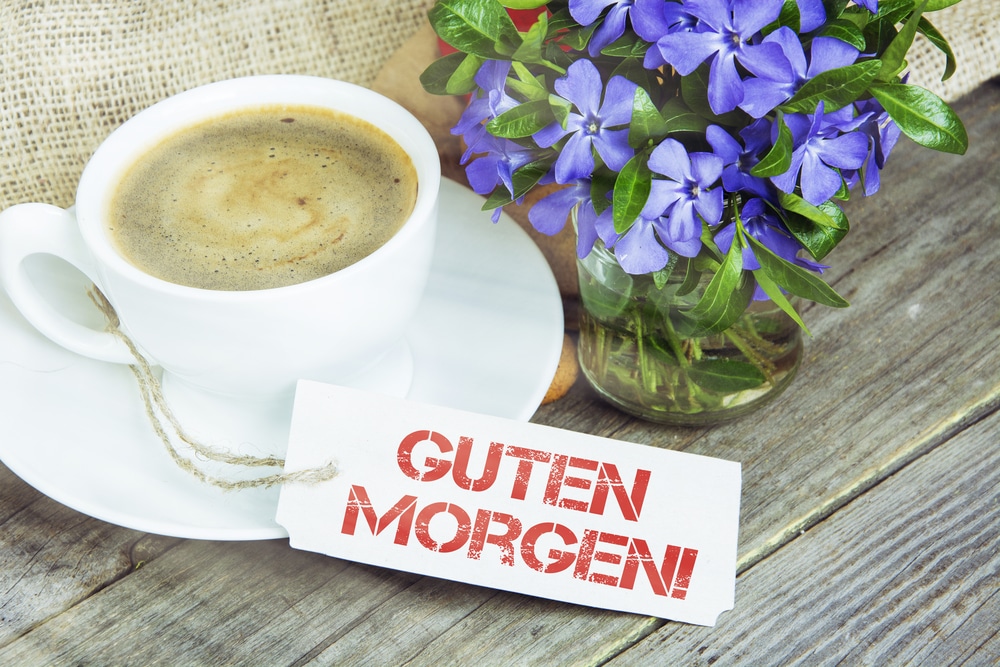 Coffee mug with vinca flowers and note Guten Morgen--good morning in German