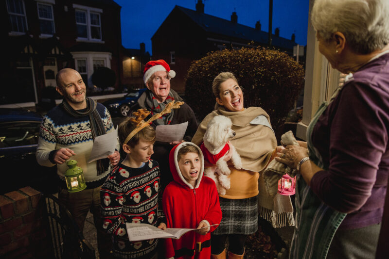 adults and children dressed up singling christmas carols