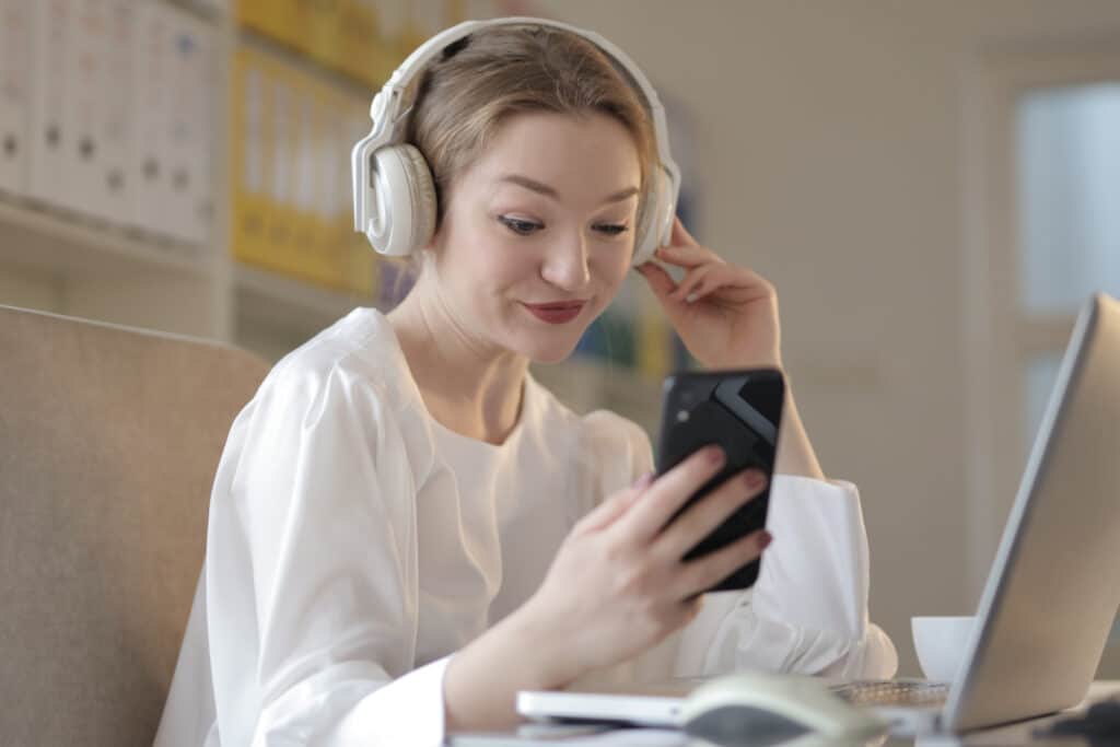 Woman wearing headphones while looking at phone