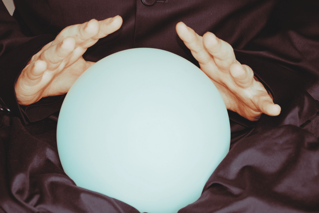 closeup-shot-of-crystal-ball-under-persons-hands-against-dark-cloth-background