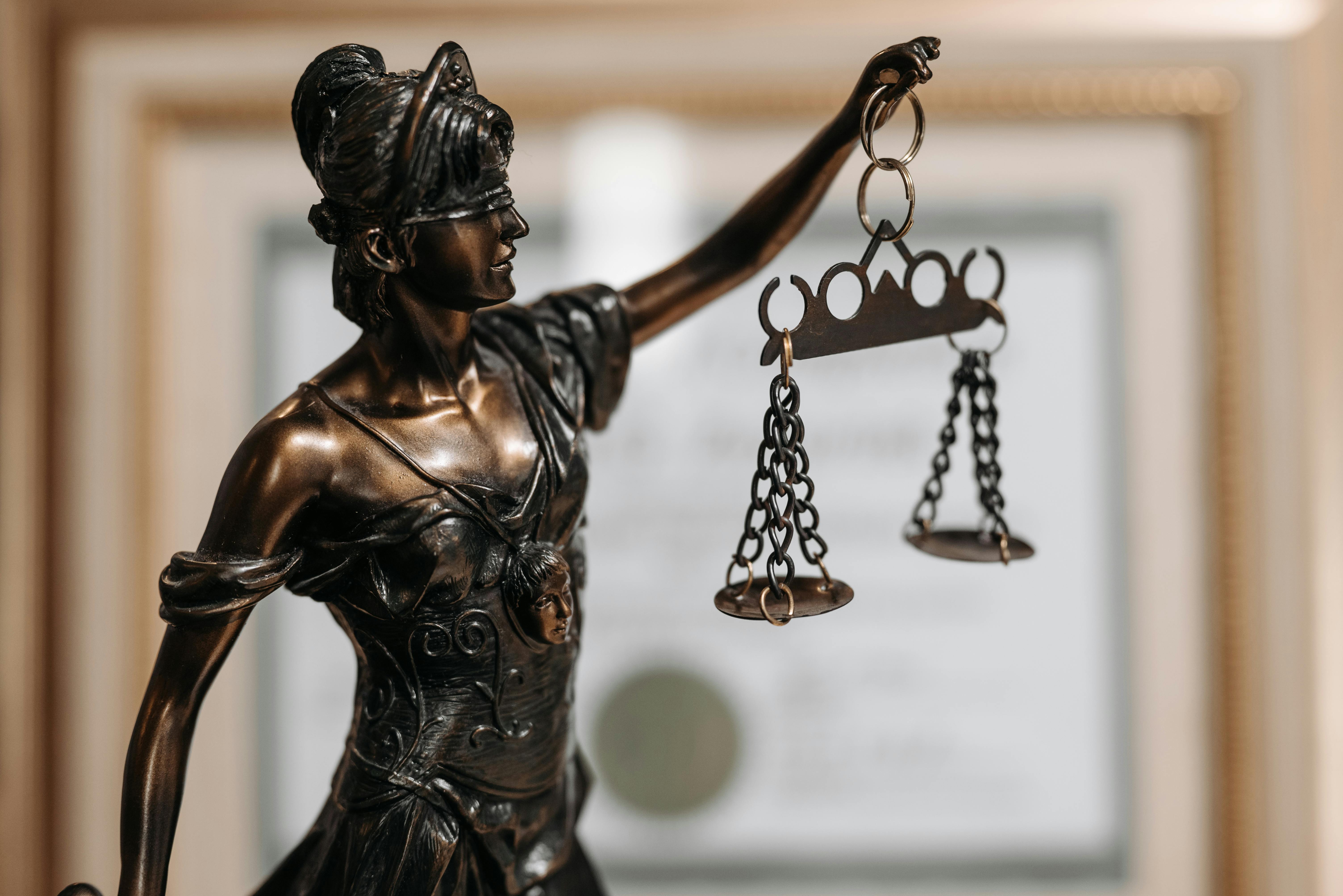 A metal statue of a woman holding up the scales of justice