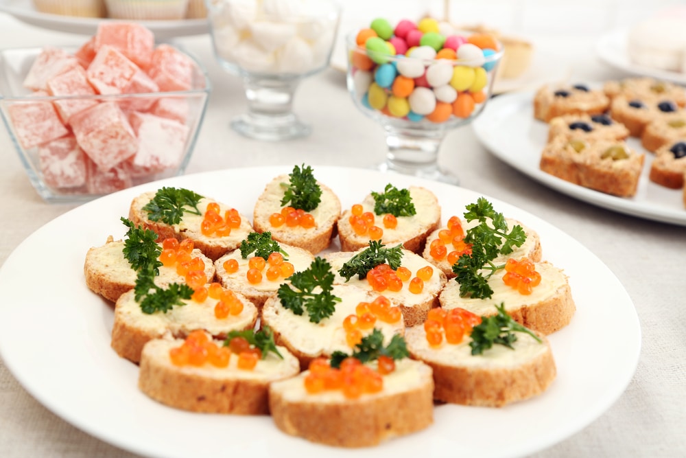 bruschetta-with-caviar-and-parsley-on-a-plate-surrounded-by-candy-and-snacks