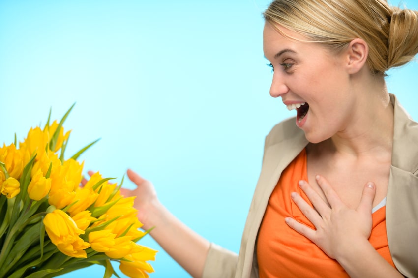 woman-surprised-open-mouth-with-hand-on-chest-looking-at-a-bouquet-of-yellow-flowers