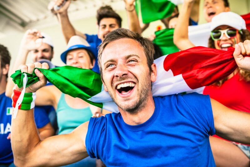 young man with friends cheering with the italian flag