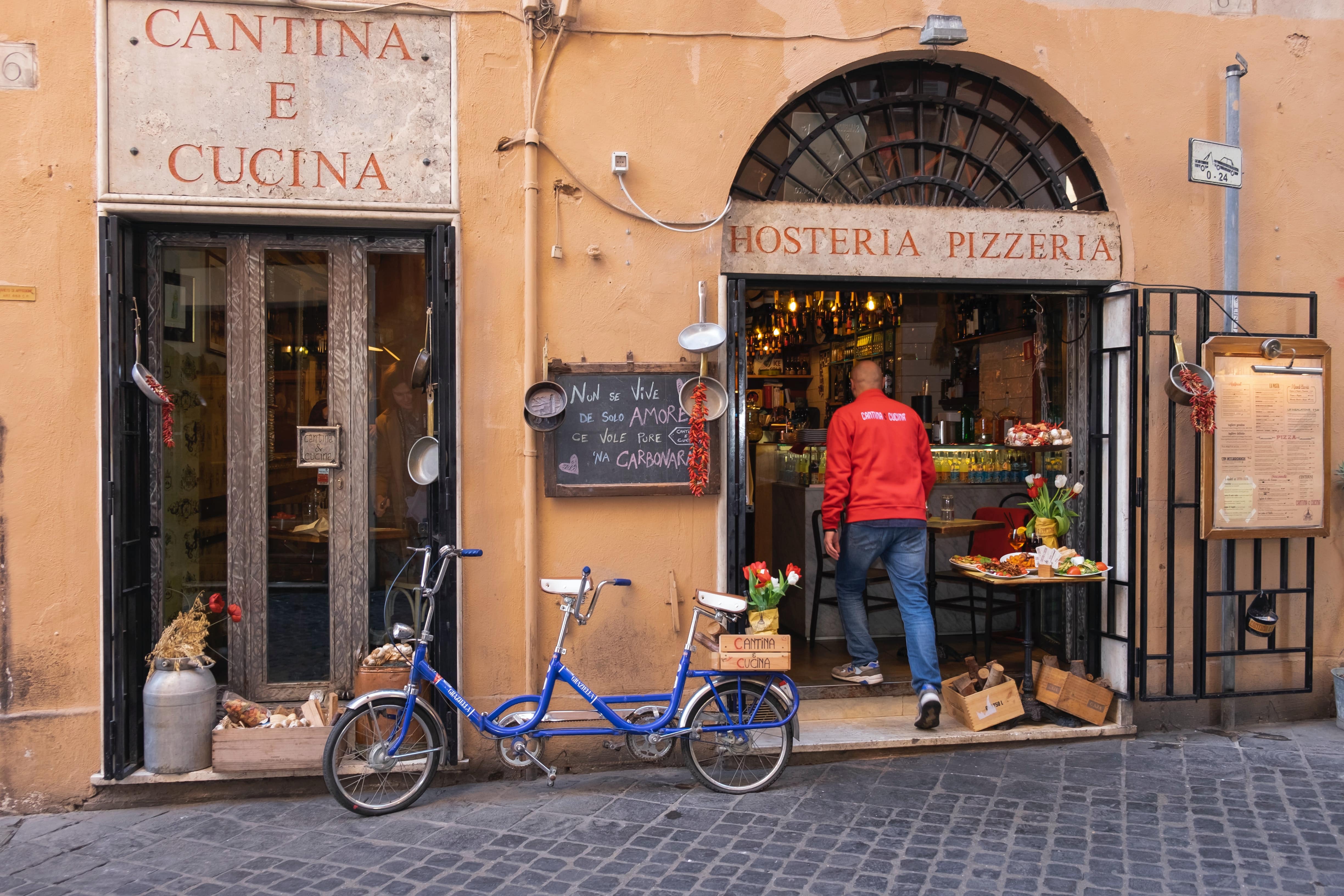 man-in-red-jacket-entering-a-pizzeria-in-rome-italy