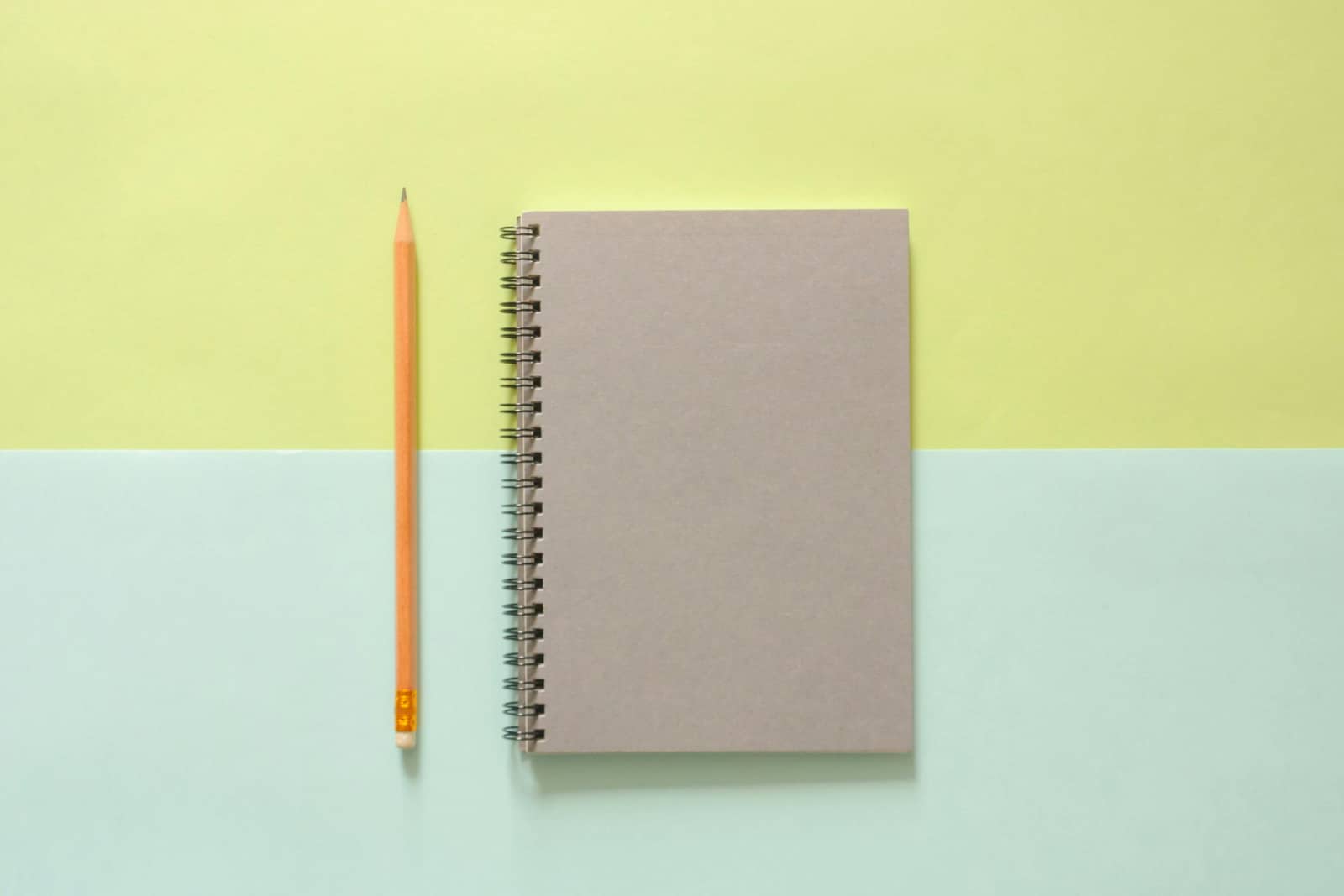 Notebook and pencil on blue and yellow background