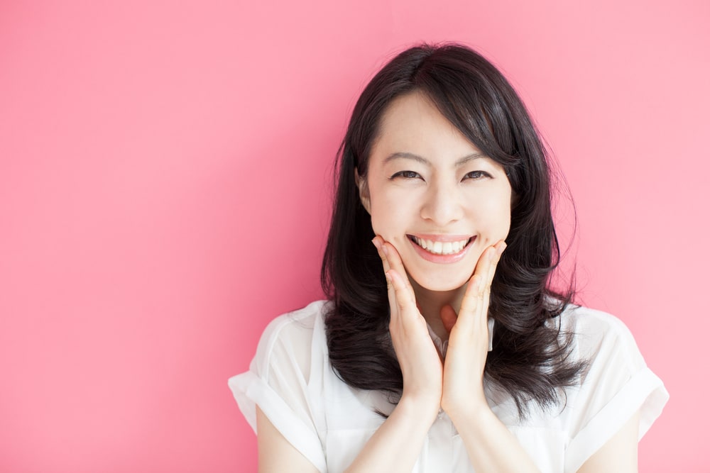 asian-woman-smiling-with-both-hands-touching-chin