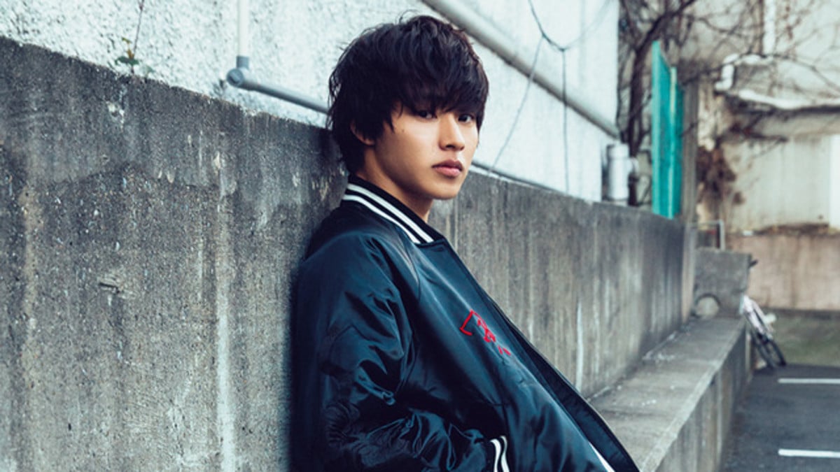 trendy-looking japanese teenager leaning against a wall
