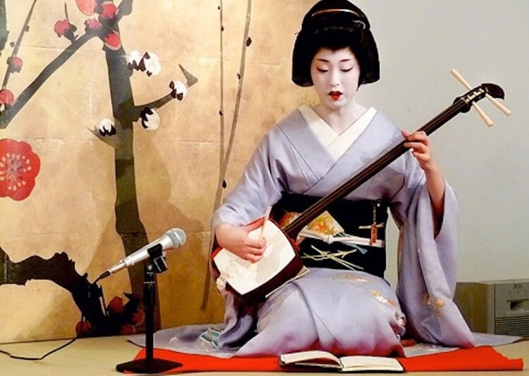 Woman playing shamisen in traditional costume