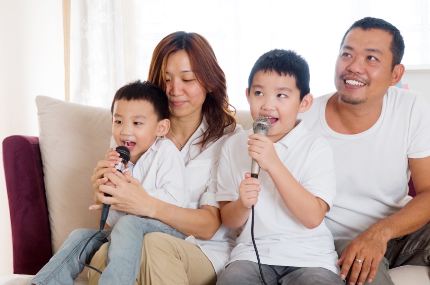 A family with two young boys singing into microphones