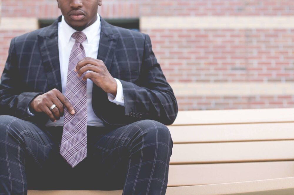 man-in-a-suit-sitting-on-a-bench-holding-his-tie