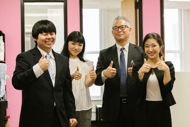 Asian men and women in business attire giving thumbs-up, yes